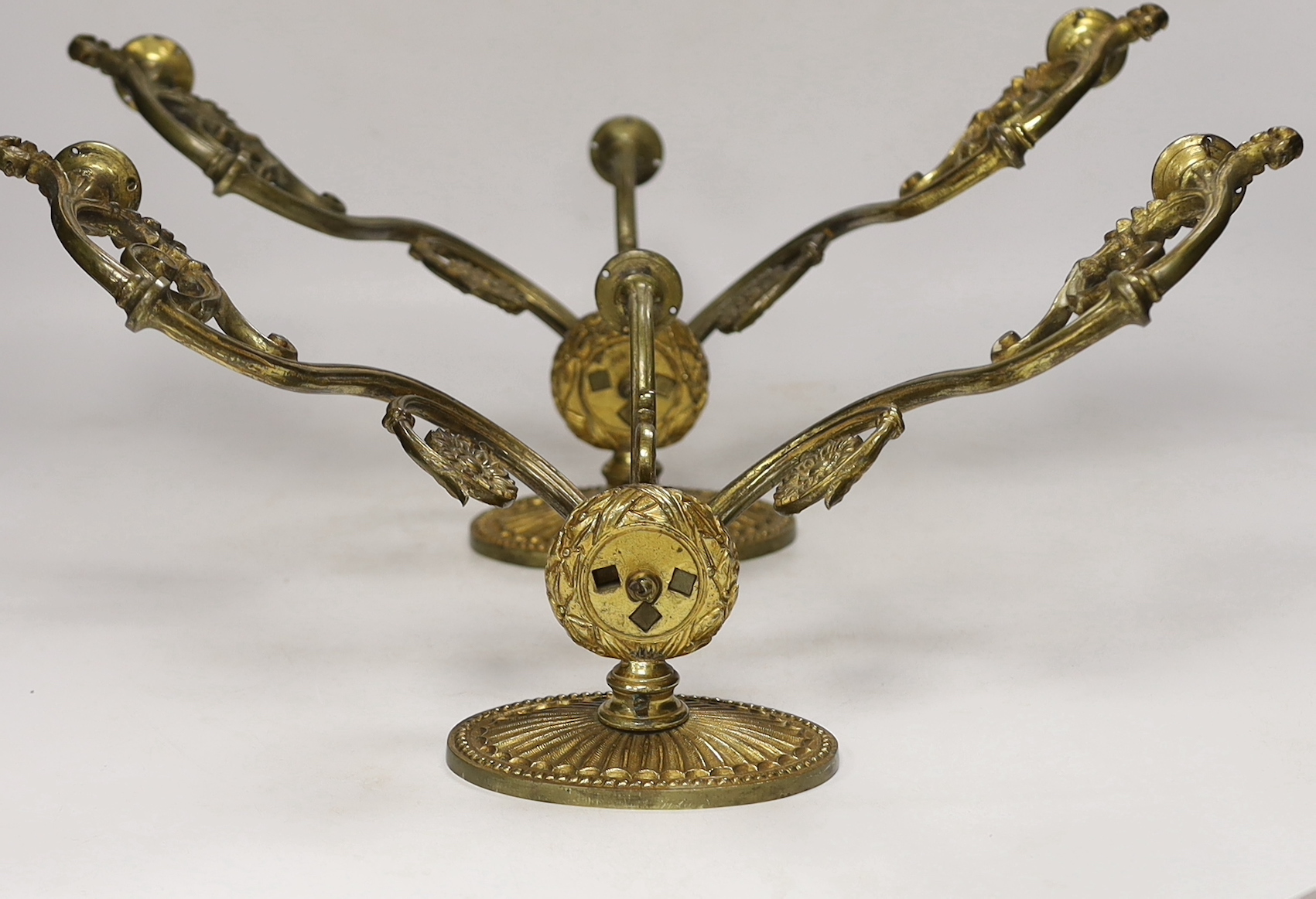 A pair of ornate brass three branch wall lights, 41cm wide